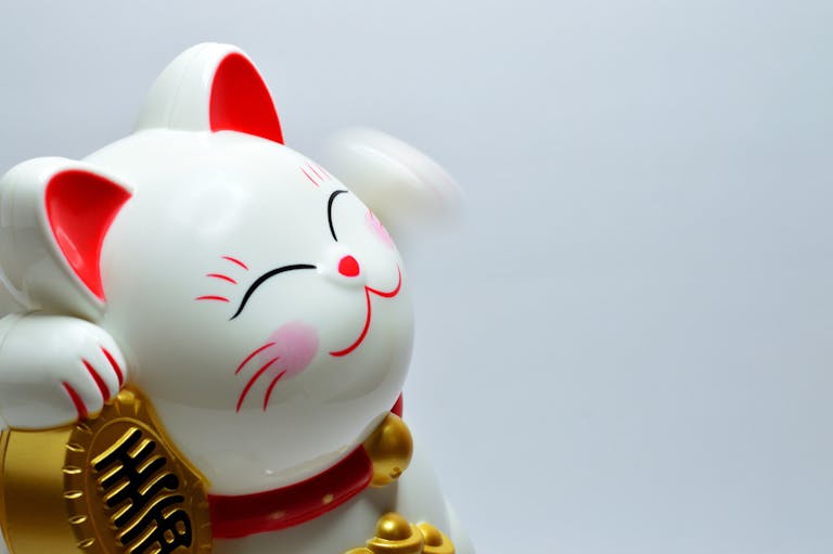 Close-up of a white Maneki Neko figurine with a raised paw symbolizing luck and fortune.