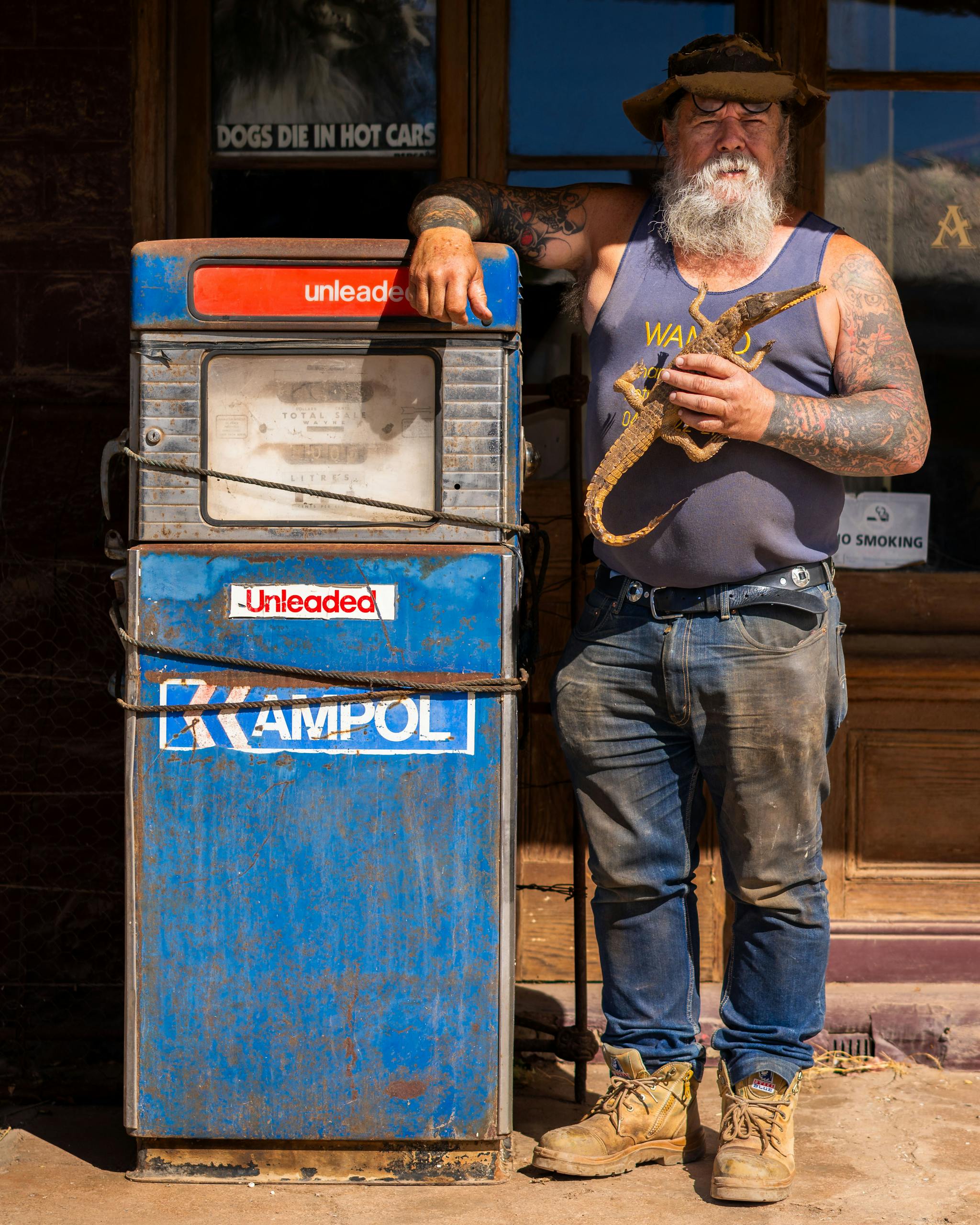 Rugged man in Australian outback with vintage Ampol petrol pump in Burra, South Australia.