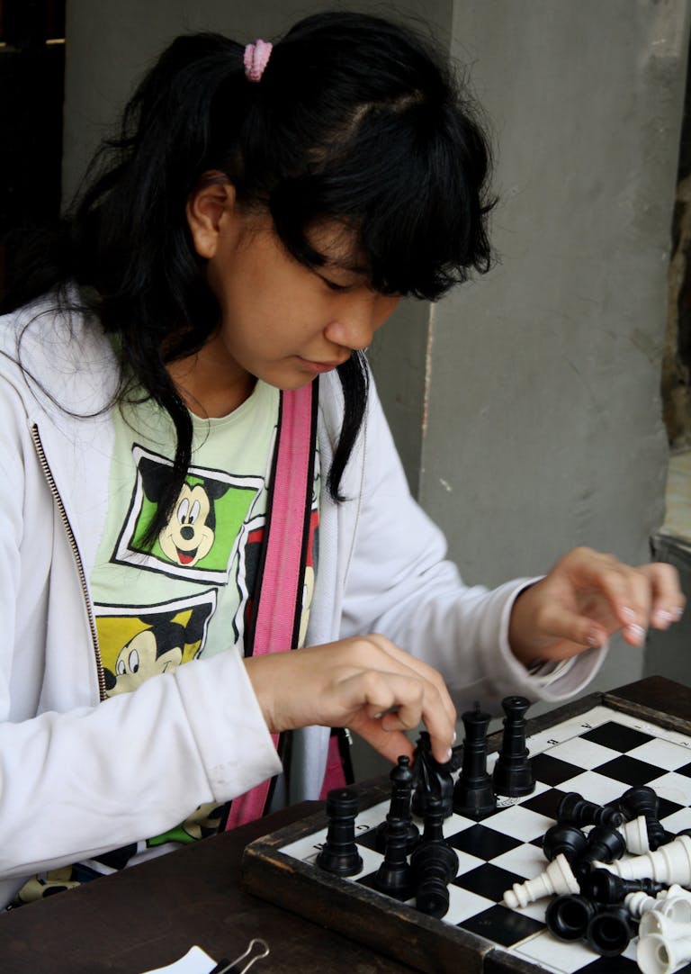 Young girl focusing on a chess game, emphasizing strategy and concentration.