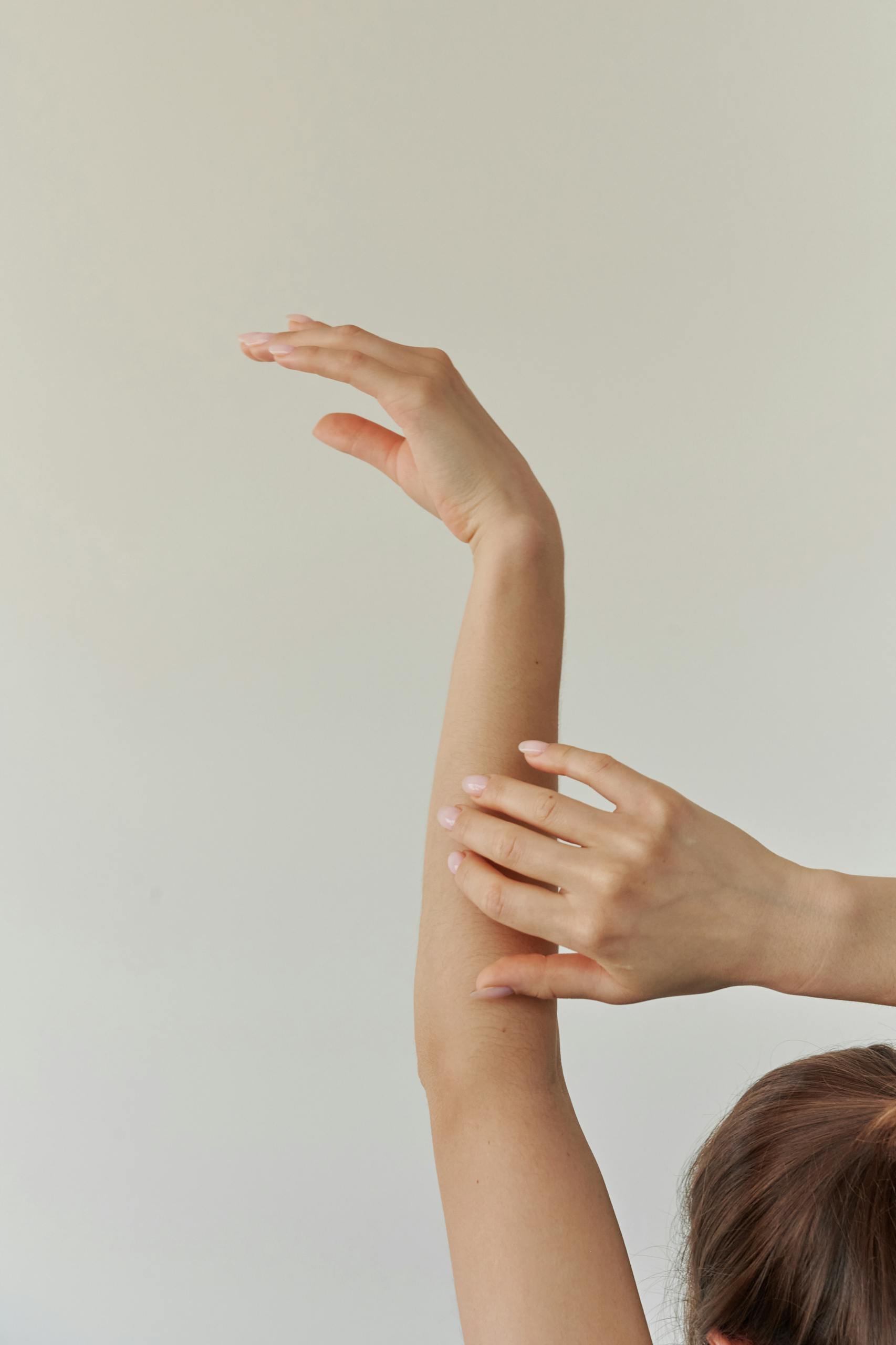 A serene composition featuring a woman's arm gracefully stretched against a neutral background.