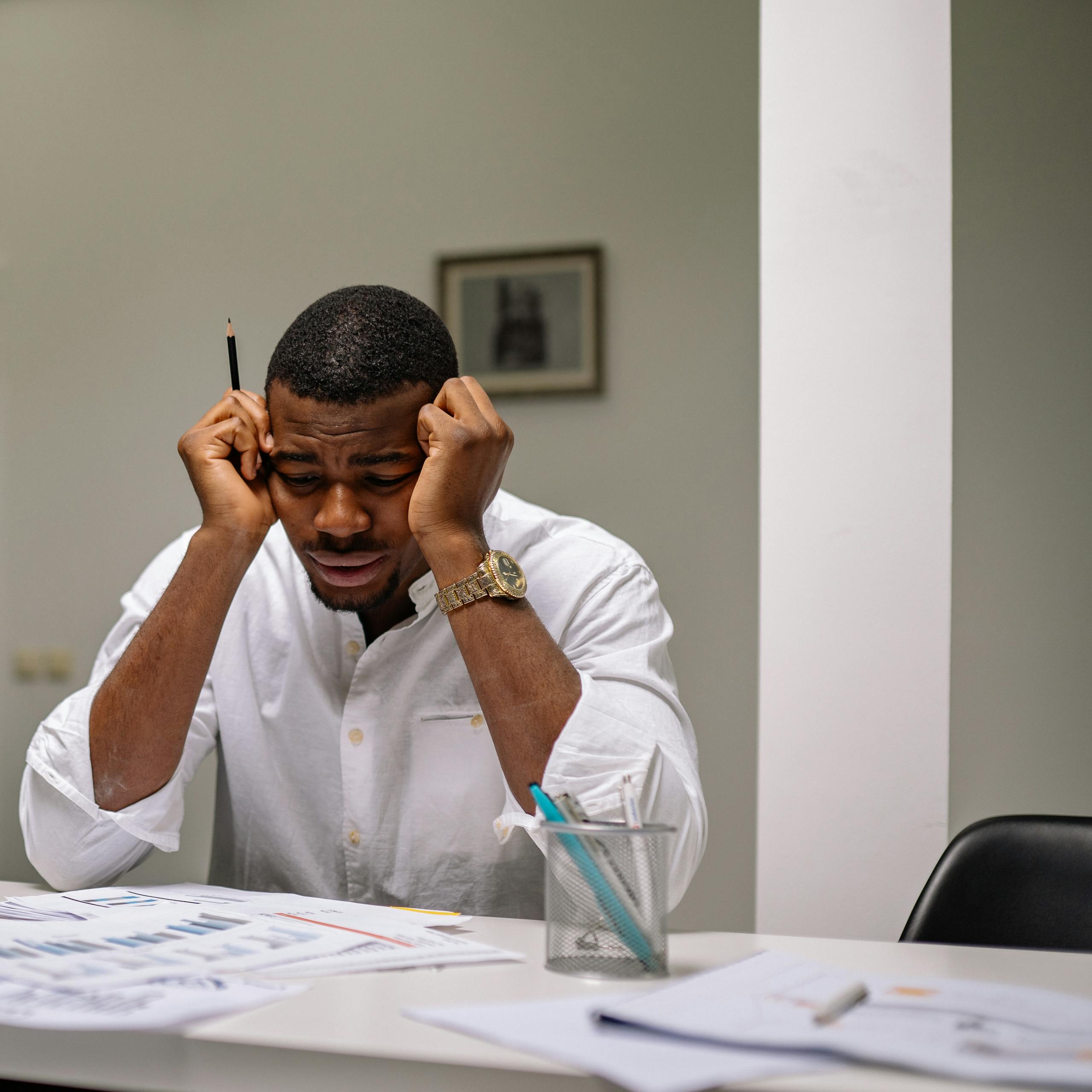 A worried businessman in corporate attire handling stress at his workspace.