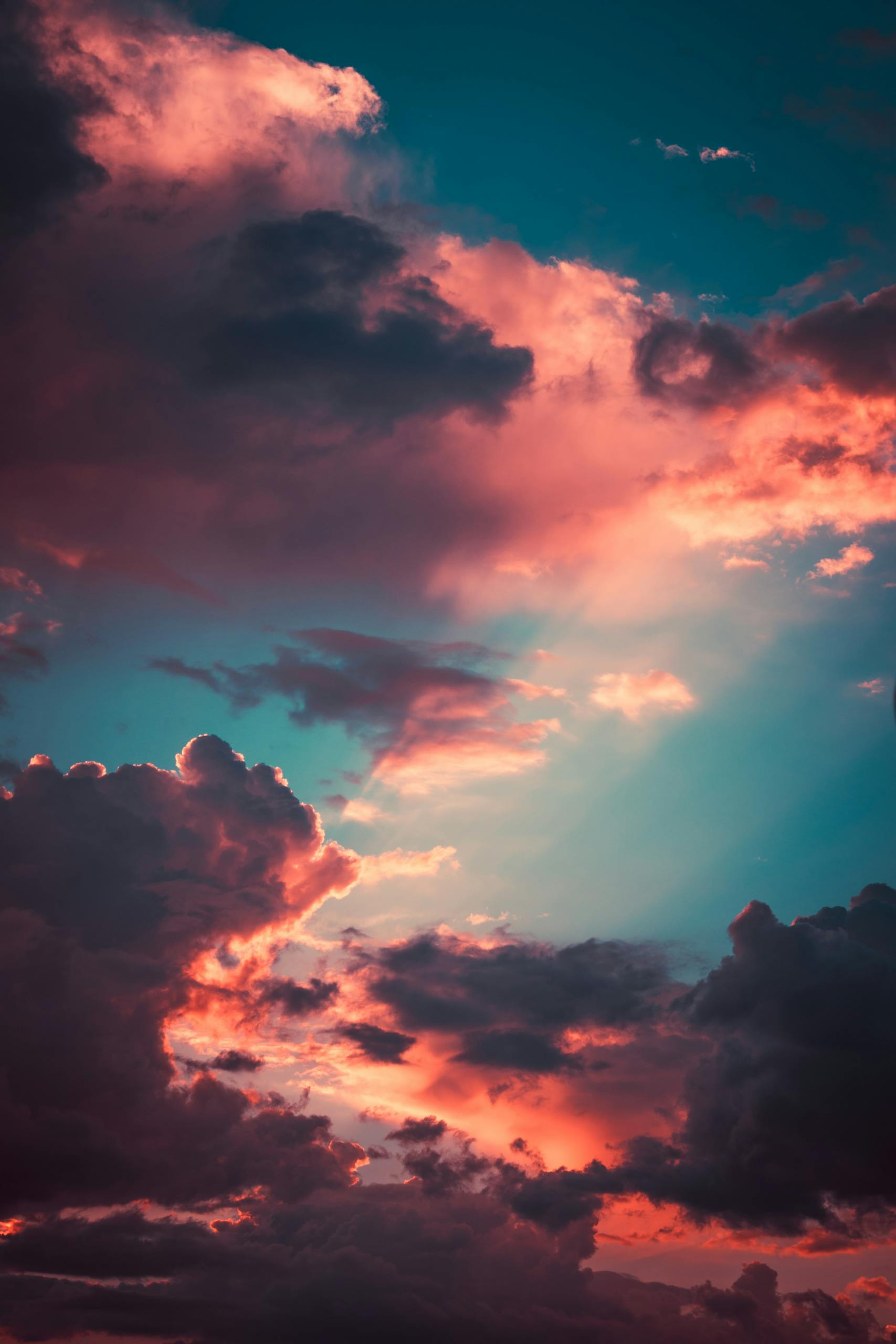 Dramatic clouds fill the sky as the sun sets, casting vibrant colors across the horizon.