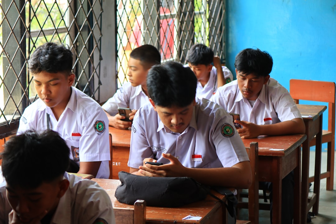Students in uniform using phones in classroom.
