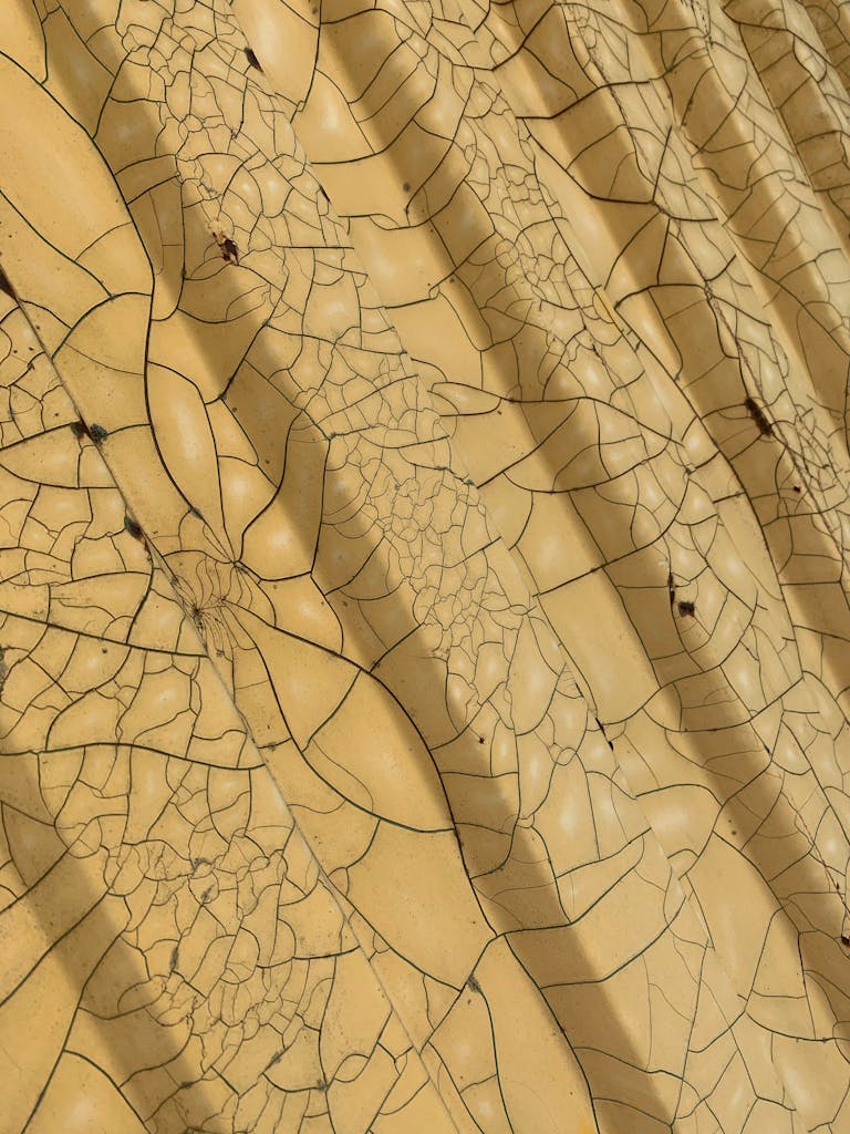 From above of geometric yellow surface with symmetric patterns and cracks as abstract background