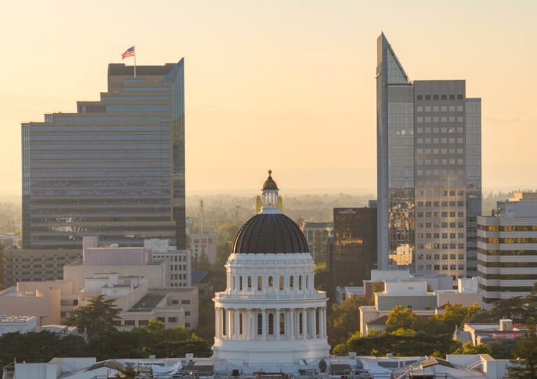 Crowd of protesters outside the California State Capitol, signs and banners visible.