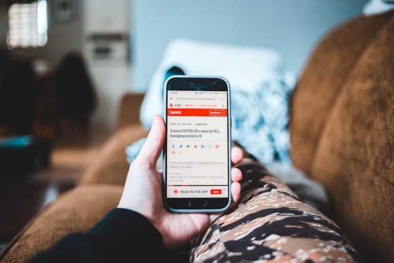 Person scrolling a news feed on a smartphone, looking at headlines.