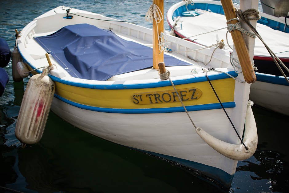 Photograph of Saint-Tropez harbor, showing sunlit boats and waterfront buildings to evoke the film's location branding.