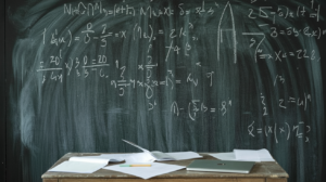 A chalkboard covered in mathematics notes and equations in a dim academic room.