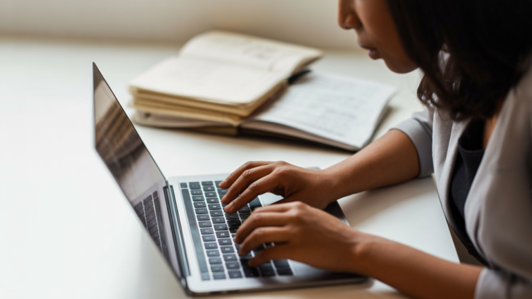 Journalist typing on a laptop in a dimly lit workspace