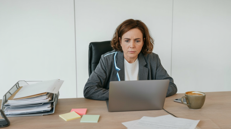 Office worker at a laptop looking confused while a chatbot interface glows on the screen.