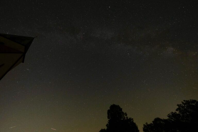 A wide night sky with the Milky Way visible above a dark landscape