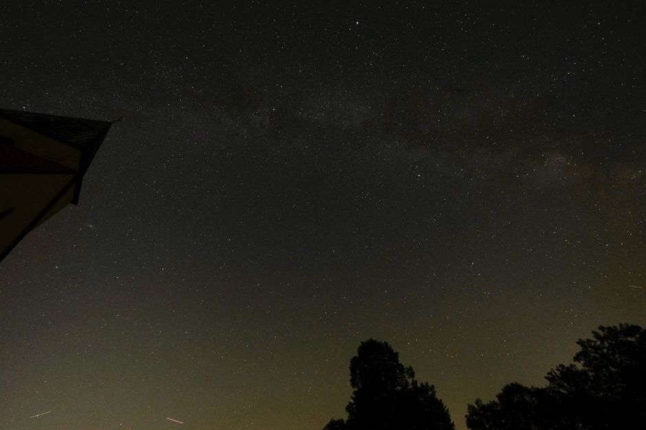A wide night sky with the Milky Way visible above a dark landscape