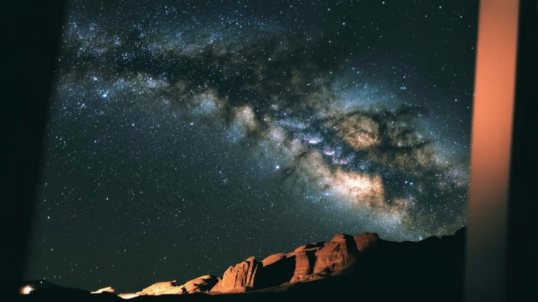 The Milky Way arching across a dark night sky above a landscape