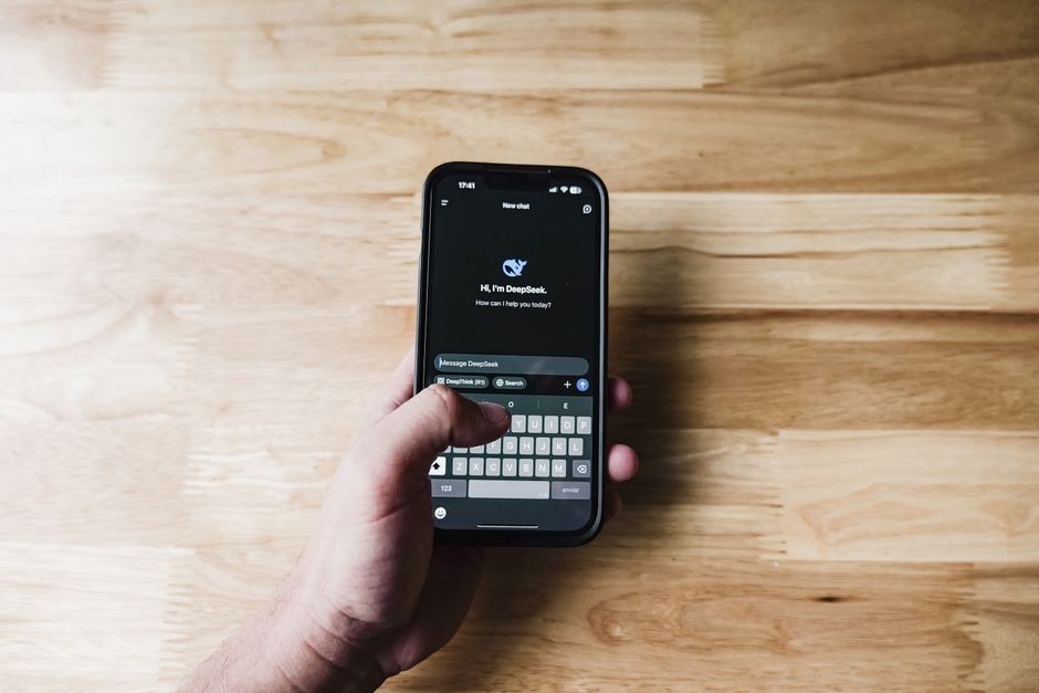ai chatbots: Person using a chatbot app on a smartphone in a modern workspace.