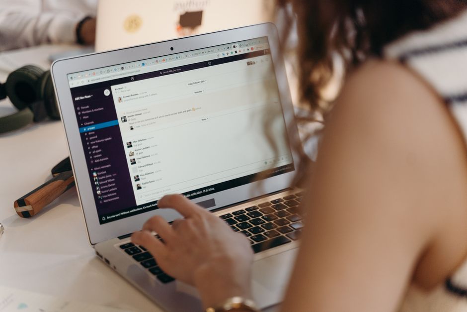 claude tag: A team workspace chat interface open on a desktop monitor, representing collaborative Slack communication.
