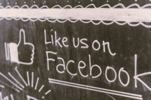 foreign meme: A person holding a smartphone showing a Facebook social feed.