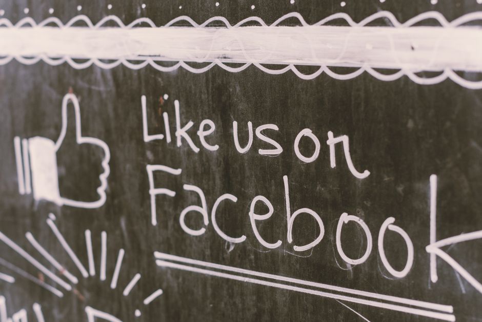 foreign meme: A person holding a smartphone showing a Facebook social feed.